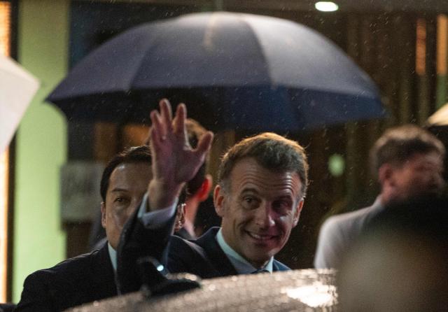French President Emmanuel Macron (C) waves to people on the street as he leaves the Ginza Motoji showroom on a rainy night in Tokyo on March 31, 2026. (Photo by ANDREW CABALLERO-REYNOLDS / AFP)