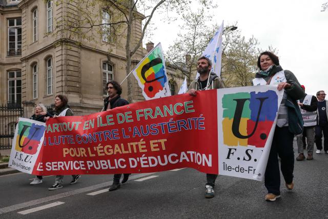 Protesters hold a banner of the Federation Syndicale Unitaire (FSU) education sector union reading "Everywhere in Il-de-France, in the fight against austerity, for equality and education public service" during a teachers' demonstration to protest against teaching post cuts and classroom closures and demand higher wages as part of the national strike in the Education nationale in Paris on March 31, 2026. (Photo by Thomas SAMSON / AFP)