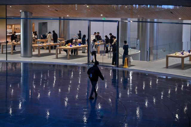 People visit an Apple store in Jing'an district in Shanghai on March 31, 2026. (Photo by HECTOR RETAMAL / AFP)