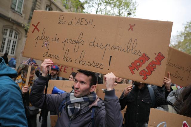 A protester holds a banner reading "No AESH (Carers for pupils with disabilities), more available teachers in classrooms! Survival mode" during a teachers' demonstration to protest against teaching post cuts and classroom closures and demand higher wages as part of the national strike in the Education nationale in Paris on March 31, 2026. (Photo by Thomas SAMSON / AFP)