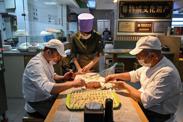 Culinary workers make dumplings in a restaurant in Jing'an district in Shanghai on March 31, 2026. (Photo by HECTOR RETAMAL / AFP)