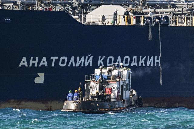 Workers on a tugboat guide the Russian oil tanker Anatoly Kolodkin as it arrives at the oil terminal in the port of Matanzas, northwestern Cuba, on March 31, 2026. The Anatoly Kolodkin, a tanker under US sanctions carrying 730,000 barrels of crude, is set to deliver the first crude shipment to Cuba since January after Washington gave the crisis-hit island a reprieve from an effective fuel blockade. (Photo by Yamil LAGE / AFP)
