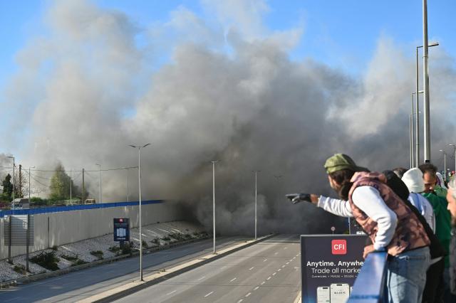 People watch smoke rising from the site of an Israeli strike that targeted a building adjacent to the highway that leads to Beirut's international airport on March 31, 2026. A strike hit a building adjacent to Beirut's main airport road on March 31, AFPTV's live broadcast showed, after the Israeli military warned it would hit a "Hezbollah facility". Lebanon was pulled into the Middle East conflict when Tehran-backed armed group Hezbollah fired rockets at Israel on March 2 in revenge for the killing of Iran's supreme leader, the opening salvo in the US-Israeli war against the Islamic republic. (Photo by FADEL itani / AFP) / 