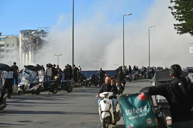 People watch smoke rising from the site of an Israeli strike that targeted a building adjacent to the highway that leads to Beirut's international airport on March 31, 2026. A strike hit a building adjacent to Beirut's main airport road on March 31, AFPTV's live broadcast showed, after the Israeli military warned it would hit a "Hezbollah facility". Lebanon was pulled into the Middle East conflict when Tehran-backed armed group Hezbollah fired rockets at Israel on March 2 in revenge for the killing of Iran's supreme leader, the opening salvo in the US-Israeli war against the Islamic republic. (Photo by FADEL itani / AFP) / 