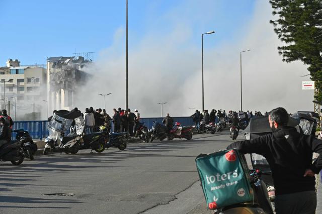 People watch smoke rising from the site of an Israeli strike that targeted a building adjacent to the highway that leads to Beirut's international airport on March 31, 2026. A strike hit a building adjacent to Beirut's main airport road on March 31, AFPTV's live broadcast showed, after the Israeli military warned it would hit a "Hezbollah facility". Lebanon was pulled into the Middle East conflict when Tehran-backed armed group Hezbollah fired rockets at Israel on March 2 in revenge for the killing of Iran's supreme leader, the opening salvo in the US-Israeli war against the Islamic republic. (Photo by FADEL itani / AFP) / 