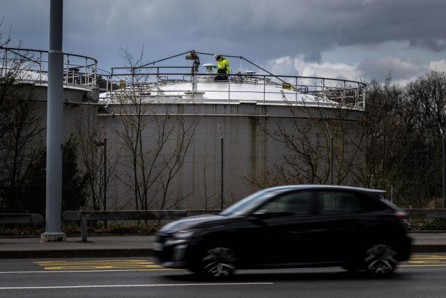 A worker operates on top of a fuel tank in Geneva on March 31, 2026. US and European stocks rose on March 31, 2026, on hopes for a quick end to the Middle East war, while oil prices steadied amid the continuing uncertainty. (Photo by Fabrice COFFRINI / AFP)