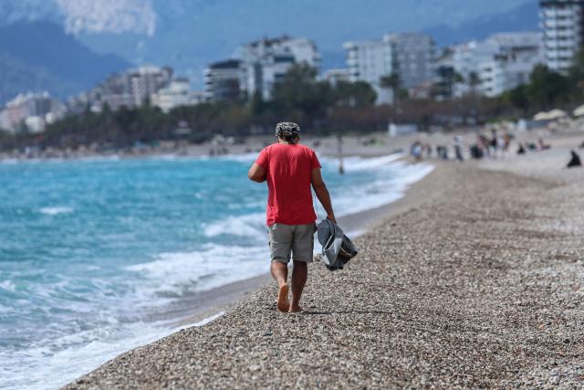 A man walks on Konyaalti beach during a sunny day in Antalya, southern Turkey, on March 30, 2026. Turkey will host the 2026 United Nations Climate Change Conference COP31 at Antalya Expo Center in the southern Turkish resort of Antalya from 9 to 20 November, 2026. (Photo by Adem ALTAN / AFP)