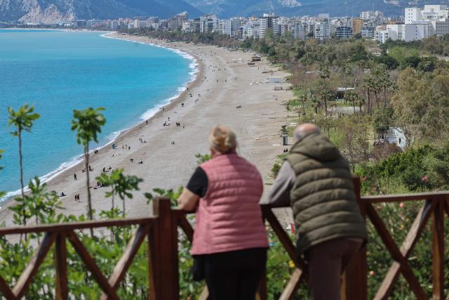 A couple look down onto Konyaalti beach in Antalya, southern Turkey, on March 30, 2026. Turkey will host the 2026 United Nations Climate Change Conference COP31 at Antalya Expo Center in the southern Turkish resort of Antalya from 9 to 20 November, 2026. (Photo by Adem ALTAN / AFP)