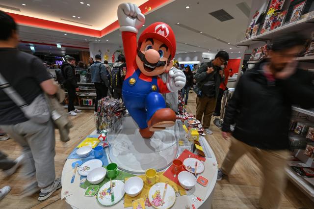 (FILES) Customers walk past a display for Super Mario by the Japanese gaming company Nintendo, at the company's official store in Tokyo's Shibuya district on April 3, 2025. Super Mario's creator Shigeru Miyamoto told AFP he had never imagined that the "little character I drew would become so big", bouncing through the decades from pixellated New York sewers to a silver-screen space epic. (Photo by Richard A. Brooks / AFP)