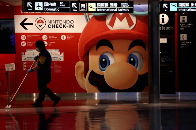(FILES) A cleaner mops the floor in front of a Nintendo’s Super Mario game character decoration at Narita Airport in China prefecture on June 1, 2021. Super Mario's creator Shigeru Miyamoto told AFP he had never imagined that the "little character I drew would become so big", bouncing through the decades from pixellated New York sewers to a silver-screen space epic. (Photo by Behrouz MEHRI / AFP)