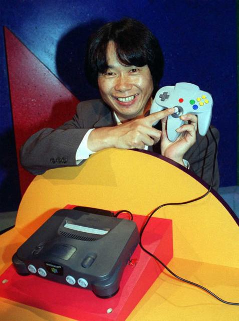 (FILES) Video game designer, Shigeru Miyamoto from Japan, points to the handset of the new Nintendo 64 flagship game, Super Mario 64, at the Los Angeles Electronic Entertainment Expo on May 15, 1996. Super Mario's creator Shigeru Miyamoto told AFP he had never imagined that the "little character I drew would become so big", bouncing through the decades from pixellated New York sewers to a silver-screen space epic. (Photo by JOHN T. BARR / AFP)