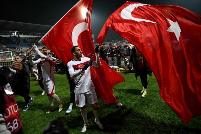 TOPSHOT - Turkey's midfielder #10 Hakan Calhanoglu waves a Turkish flag after winning at the end of the FIFA World Cup 2026 European qualification final football match between Kosovo and Turkey at the Fadil Vokrri stadium in Pristina on March 31, 2026. (Photo by Armend NIMANI / AFP)