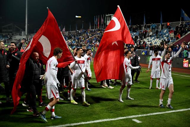 Turkey's forward #11 Kenan Yildiz (L) and Turkey's midfielder #10 Hakan Calhanoglu (R) wave Turkish flags as they celebrate after winning at the end of the FIFA World Cup 2026 European qualification final football match between Kosovo and Turkey at the Fadil Vokrri stadium in Pristina on March 31, 2026. (Photo by Armend NIMANI / AFP)