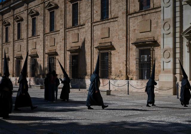 Penitents of the 'Los Estudiantes' brotherhood arrive to take part in a procession during Holy Week in Seville, Spain, on March 31 2026. Spain's colourful Holy Week celebrations started this week, featuring centuries-old processions of the faithful carrying flower-covered floats topped with statues of Christ or the Virgin Mary that draw huge crowds. Organised by various religious brotherhoods, or "confradias", the parades are held across the country in the week leading up to Easter Sunday, which this year in the Roman Catholic Church falls on April 5, 2026. (Photo by Cristina Quicler / AFP)