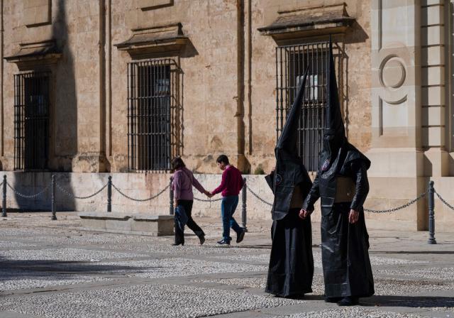 TOPSHOT - Penitents of the 'Los Estudiantes' brotherhood arrive to take part in a procession during Holy Week in Seville, Spain, on March 31 2026. Spain's colourful Holy Week celebrations started this week, featuring centuries-old processions of the faithful carrying flower-covered floats topped with statues of Christ or the Virgin Mary that draw huge crowds. Organised by various religious brotherhoods, or "confradias", the parades are held across the country in the week leading up to Easter Sunday, which this year in the Roman Catholic Church falls on April 5, 2026. (Photo by Cristina Quicler / AFP)