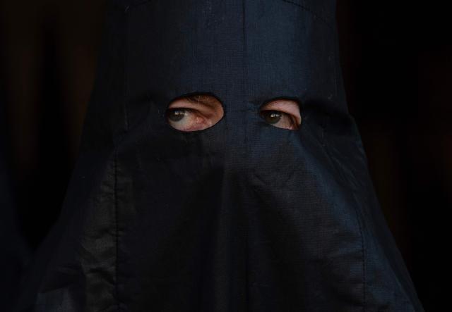 A penitents of the 'Los Estudiantes' brotherhood looks on while taking part in a procession during Holy Week in Seville, Spain, on March 31 2026. Spain's colourful Holy Week celebrations started this week, featuring centuries-old processions of the faithful carrying flower-covered floats topped with statues of Christ or the Virgin Mary that draw huge crowds. Organised by various religious brotherhoods, or "confradias", the parades are held across the country in the week leading up to Easter Sunday, which this year in the Roman Catholic Church falls on April 5, 2026. (Photo by Cristina Quicler / AFP)