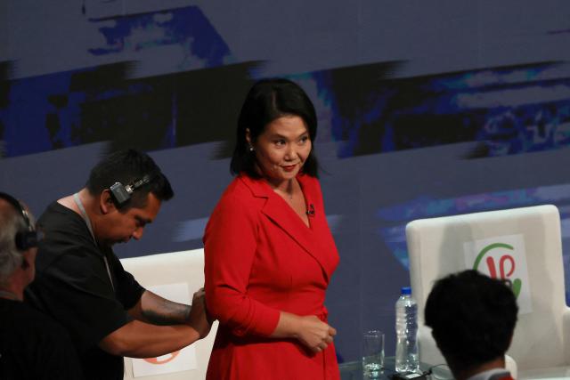 Peru's presidential candidate Keiko Fujimori, for the Fuerza Popular party is being helped with her microphone ahead of the second round of debates on education and employment at the Lima Convention Center in Lima on March 31, 2026. Peru will hold presidential elections on April 12. (Photo by Connie FRANCE / AFP)