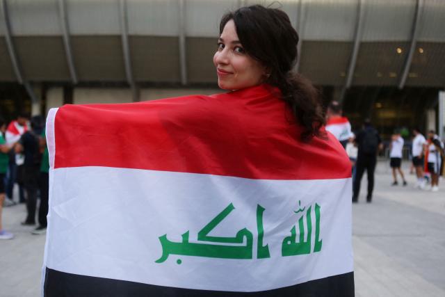 An Iraqi fan covers herself with a national flag ahead of the 2026 FIFA World Cup qualifiers final playoff football match between Iraq and Bolivia at the BBVA Stadium in Guadalupe, Nuevo Leon state, Mexico, on March 31, 2026. (Photo by Julio Cesar AGUILAR / AFP)