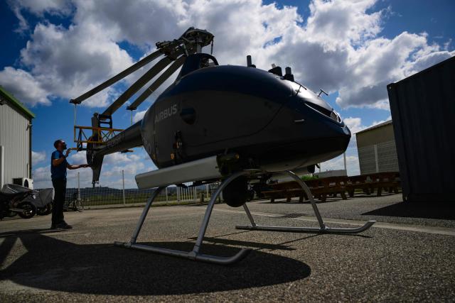An employee inspects an Airbus VSR700 uncrewed aerial system (UAS) helicopter drone at the Survey Copter factory, an Airbus subsidiary in Pierrelatte, southern France on March 31, 2026. At Survey Copter, a French SME integrated into Airbus, the European aerospace corporation is leaning on its know-how in helicopters to develop drones — which have become the sinews of modern warfare — and to make them cooperate with manned aircraft. (Photo by OLIVIER CHASSIGNOLE / AFP)