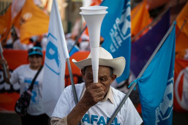 A supporter of Peru's presidential candidate Rafael Lopez Aliaga, for the Renovacion Popular party, is seen outside the Lima Convention Center during the second round of debates on education and employment in Lima on March 31, 2026. Peru will hold presidential elections on April 12. (Photo by ERNESTO BENAVIDES / AFP)