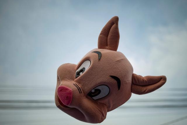 A supporter of Peru's presidential candidate Rafael Lopez Aliaga, for the Renovacion Popular party, throws a pig mask into the air outside the Lima Convention Center during the second round of debates on education and employment in Lima on March 31, 2026. Peru will hold presidential elections on April 12. (Photo by ERNESTO BENAVIDES / AFP)