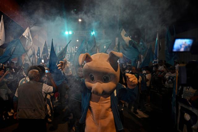 A supporter of Peru's presidential candidate Rafael Lopez Aliaga, for the Renovacion Popular party, wears a pig mask outside the Lima Convention Center during the second round of debates on education and employment in Lima on March 31, 2026. Peru will hold presidential elections on April 12. (Photo by ERNESTO BENAVIDES / AFP)