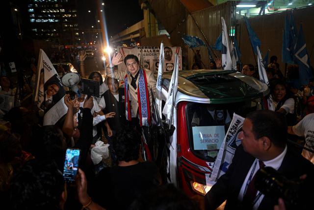 Peru's presidential candidate Herbert Caller, for the Patriotic Party of Peru, waves from a "tuktuk" upon his arrival for the second round of debates on education and employment at the Lima Convention Center in Lima on March 31, 2026. Peru will hold presidential elections on April 12. (Photo by ERNESTO BENAVIDES / AFP)