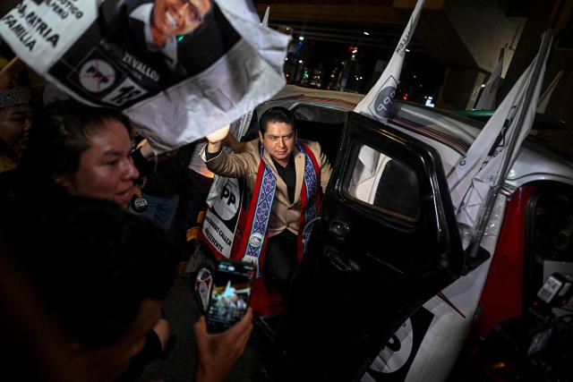 Peru's presidential candidate Herbert Caller, for the Patriotic Party of Peru, waves from a "tuktuk" upon his arrival for the second round of debates on education and employment at the Lima Convention Center in Lima on March 31, 2026. Peru will hold presidential elections on April 12. (Photo by ERNESTO BENAVIDES / AFP)