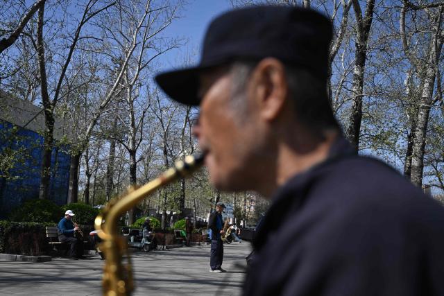 People gather to play wind instruments at a park during the spring season in Beijing on April 1, 2026. (Photo by Pedro PARDO / AFP)
