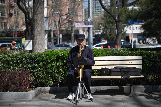A man plays a saxophone at a park during the spring season in Beijing on April 1, 2026. (Photo by Pedro PARDO / AFP)