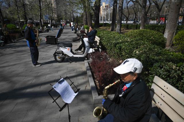 People gather to play wind instruments at a park during the spring season in Beijing on April 1, 2026. (Photo by Pedro PARDO / AFP)