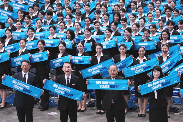 All Nippon Airways executives (front row) and new employees of ANA Group attend an annual entrance ceremony at an aircraft hangar of Tokyo's Haneda Airport on April 1, 2026, the first day of the new fiscal year. (Photo by Kazuhiro NOGI / AFP)