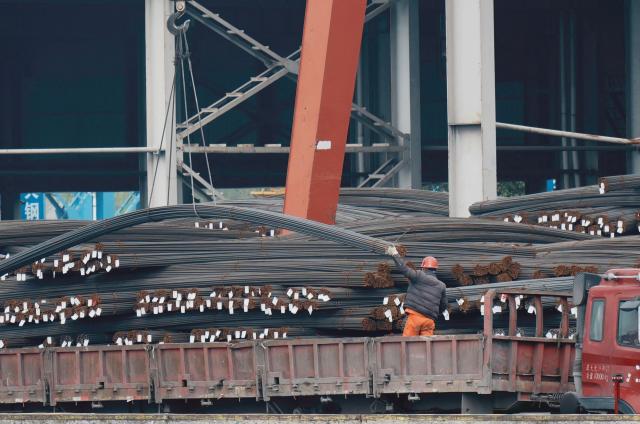 A worker handles steel rods at a steel market in Hangzhou, in eastern China's Zhejiang province, on March 31, 2026. (Photo by -STR / CN-STR / AFP) / China OUT