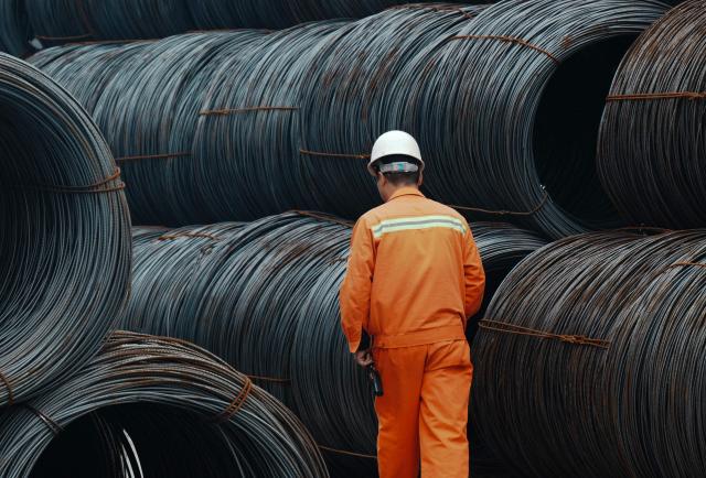 A worker walks between steel coils at a steel market in Hangzhou, in eastern China's Zhejiang province, on March 31, 2026. (Photo by -STR / CN-STR / AFP) / China OUT