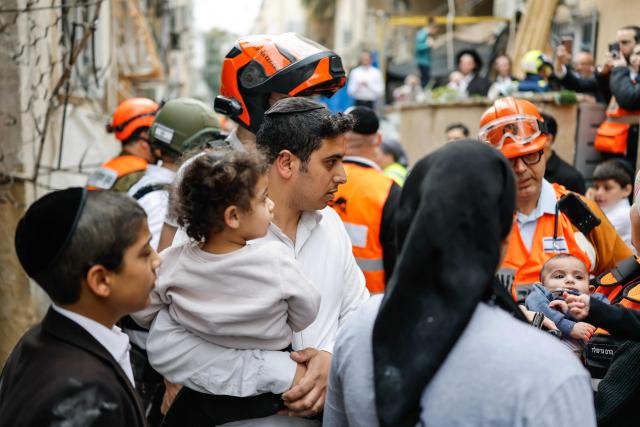 First responders and residents carry children out of an apartment building that was hit at the scene of an impact following an Iranian strike over Bnei Brak in central Israel on April 1, 2026. The Israeli military said its air defences responded to a missile attack from Iran on April 1, with warning sirens activated across central Israel. (Photo by Marco Longari / AFP) / 