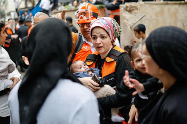 First responders and residents carry children out of an apartment building that was hit at the scene of an impact following an Iranian strike over Bnei Brak in central Israel on April 1, 2026. The Israeli military said its air defences responded to a missile attack from Iran on April 1, with warning sirens activated across central Israel. (Photo by Marco Longari / AFP) / 