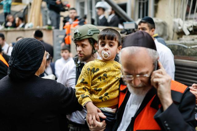 A child looks on after being carried out of an apartment building that was hit at the scene of an impact following an Iranian strike over Bnei Brak in central Israel on April 1, 2026. The Israeli military said its air defences responded to a missile attack from Iran on April 1, with warning sirens activated across central Israel. (Photo by Marco Longari / AFP) / 