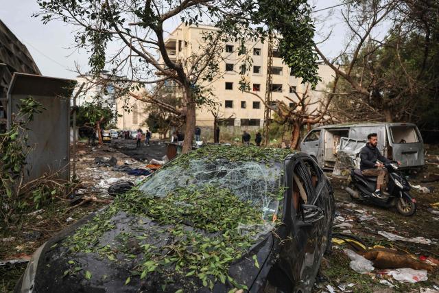 TOPSHOT - A man rides past the wreckage of vehicles at the site of an Israeli strike in Beirut on April 1, 2026. Lebanon was drawn into the Middle East war on March 2 when Tehran-backed militant group Hezbollah launched attacks on Israel to avenge the killing of the Iranian leader. Israel has responded with broad strikes across Lebanon and a ground offensive. (Photo by Anwar AMRO / AFP)