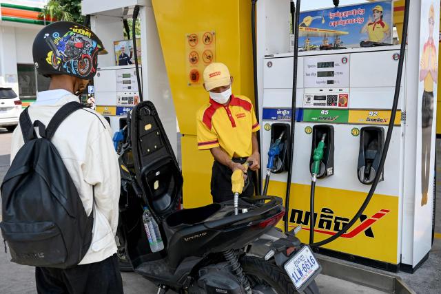 An employee pumps gasoline into the motorbike of a customer at a fuel station in Phnom Penh on April 1, 2026. Cambodia's diesel price on April 1 reached double its level at the start of the Middle East war after the latest government increase, official figures showed, raising concerns among farmers ahead of ploughing season. (Photo by TANG CHHIN Sothy / AFP)