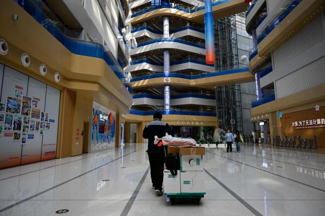 A man pulls a trolley during a tour at the Alibaba office in Beijing on April 1, 2026. (Photo by WANG Zhao / AFP)