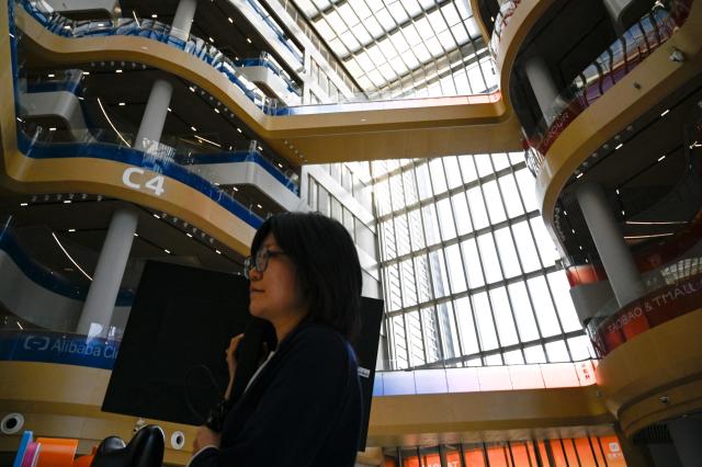 An employee walks past during a tour at the Alibaba office in Beijing on April 1, 2026. (Photo by WANG Zhao / AFP)