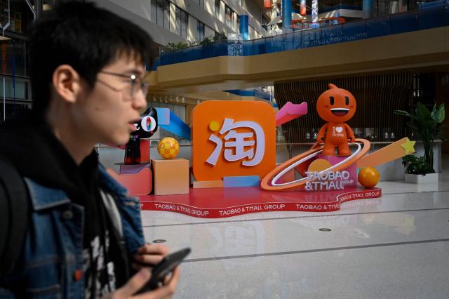 A man walks past a Taobao and Tmall installation during a tour at the Alibaba office in Beijing on April 1, 2026. (Photo by WANG Zhao / AFP)