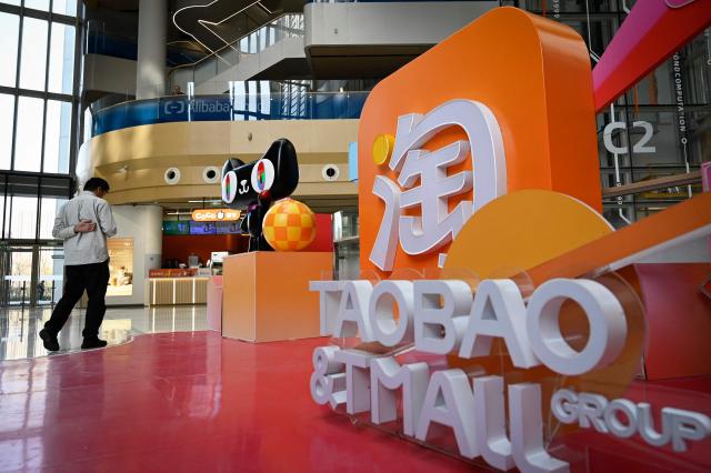 A man walks past a Taobao and Tmall installation during a tour at the Alibaba office in Beijing on April 1, 2026. (Photo by WANG Zhao / AFP)