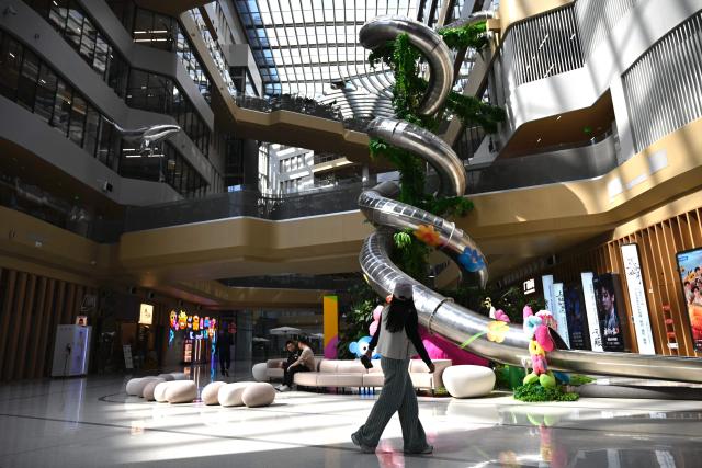 A woman walks past during a tour at the Alibaba office in Beijing on April 1, 2026. (Photo by WANG Zhao / AFP)