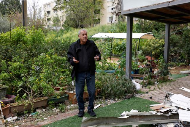 Israeli resident Haim speaks outside his house that was hit by a Hezbollah rocket in the northern town of Kiryat Shmona near the border with Lebanon on March 30, 2026. Lives paced by sirens and confined within four walls. The city is empty, deserted by its young people. In Kiryat Shmona, on the frontline of the war between Israel and Lebanon's Hezbollah, those who have stayed can't take it anymore and feel "neglected" by the government. (Photo by Jalaa MAREY / AFP)