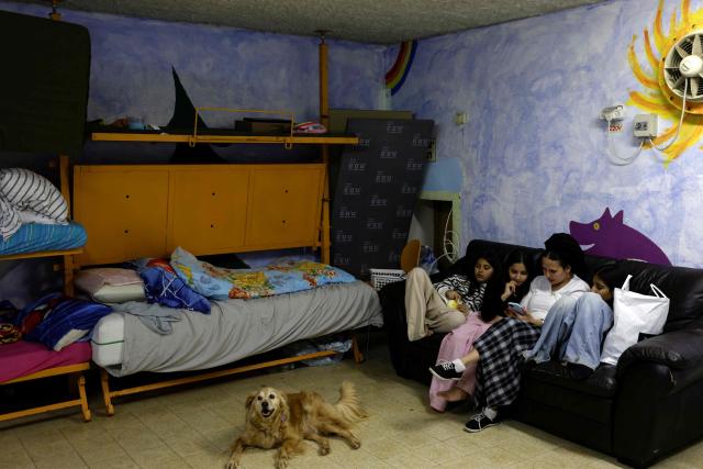 Olga sits with her children inside a shelter in the northern Israeli town of Kiryat Shmona near the border with Lebanon on March 30, 2026. Lives paced by sirens and confined within four walls. The city is empty, deserted by its young people. In Kiryat Shmona, on the frontline of the war between Israel and Lebanon's Hezbollah, those who have stayed can't take it anymore and feel "neglected" by the government. (Photo by Jalaa MAREY / AFP)