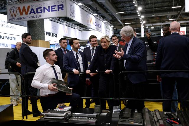 Far-right Rassemblement National (RN) parliamentary group president Marine Le Pen (C) and Rassemblement National's MP Jean-Philippe Tanguy (2nd L) are given a tour as they visit the Global Industrie trade show at the Paris Nord Villepinte exhibition centre in Villepinte,  northeast of Paris, on April 1, 2026. (Photo by STEPHANE DE SAKUTIN / AFP)