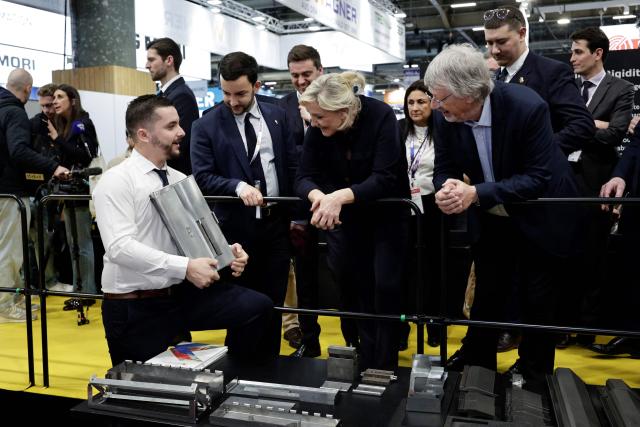 Far-right Rassemblement National (RN) parliamentary group president Marine Le Pen (C) and Rassemblement National's MP Jean-Philippe Tangu (2nd L) are given a tour as they visit the Global Industrie trade show at the Paris Nord Villepinte exhibition centre in Villepinte,  northeast of Paris, on April 1, 2026. (Photo by STEPHANE DE SAKUTIN / AFP)