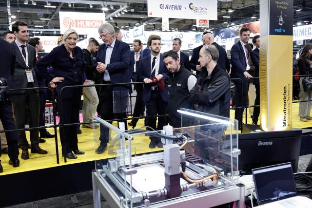 Far-right Rassemblement National (RN) parliamentary group president Marine Le Pen (2nd L) and Rassemblement National's MP Jean-Philippe Tanguy (4th L) are given a tour as they visit the Global Industrie trade show at the Paris Nord Villepinte exhibition centre in Villepinte,  northeast of Paris, on April 1, 2026. (Photo by STEPHANE DE SAKUTIN / AFP)