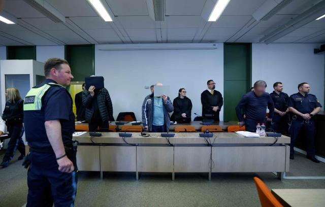 Defendants 71-year-old Joachim K (L), 62-year-old Rainer S (C) and 60-year-old Achim M (R) stand in the courtroom prior to the start of their trial for backing the self-styled "United Patriots" group, part of Germany's extremist Reichsbuerger scene, on April 1, 2026 at the higher Regional court of Munich, southern Germany. The group, referred to by investigators as the Kaiserreichsgruppe or "Imperial Group", was allegedly committed to forcibly establishing a new authoritarian Germany based on the old 1871 Imperial Constitution. (Photo by Michaela Stache / AFP) / GERMAN COURT REQUESTS THAT THE FACE OF THE DEFENDANT MUST BE MADE UNRECOGNISABLE
